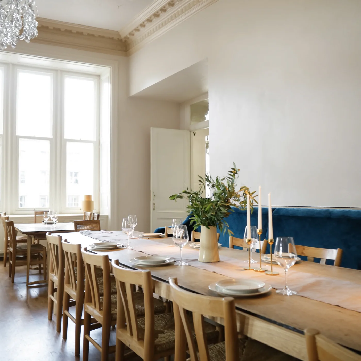 An intimate private dining room with a complete oak table and navy banquette, set before guests arrive