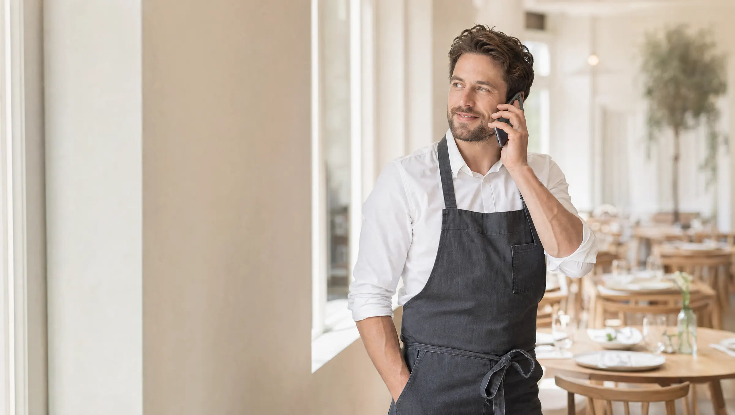 A restaurant host takes a phone call in a bright dining room.